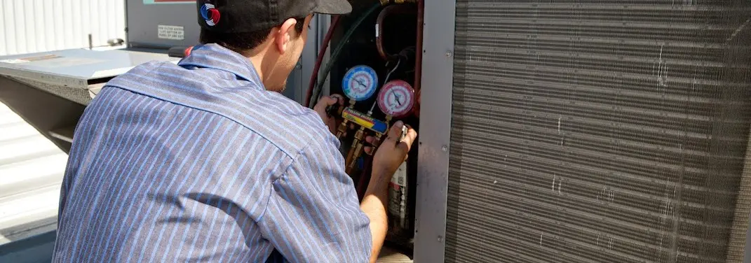 HVAC technician servicing a condenser unit in South Boston