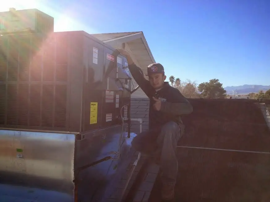 HVAC technician performing AC Tune-Up on a rooftop unit in South Boston